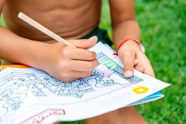 Criança a colorir uma atividade do caderno Rabiskas com lápis de cor