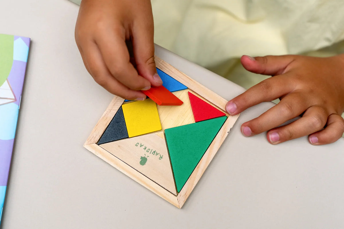Criança a montar o tangram de madeira do Kit Rabiskas Nível 2