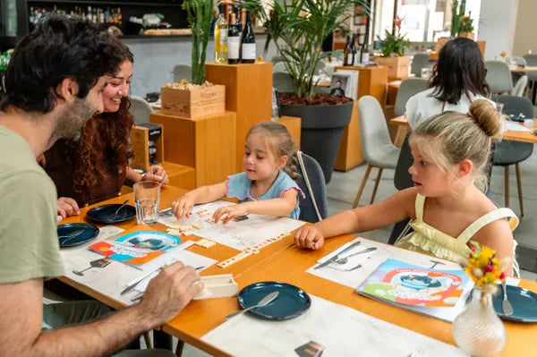 Família à mesa a brincar com o kit Rabiskas